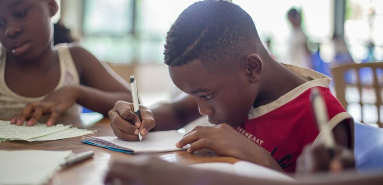 boy writing on printer paper near girl