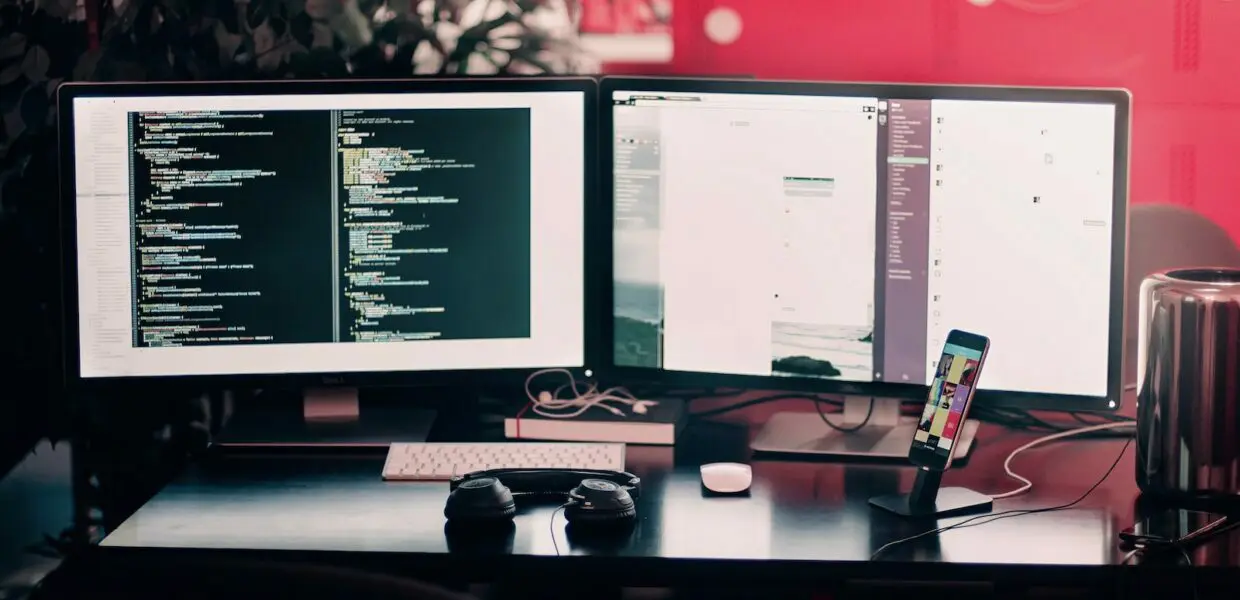 two black computer monitors on black table