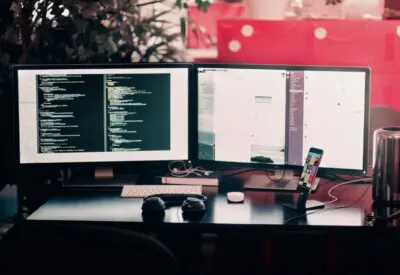 two black computer monitors on black table