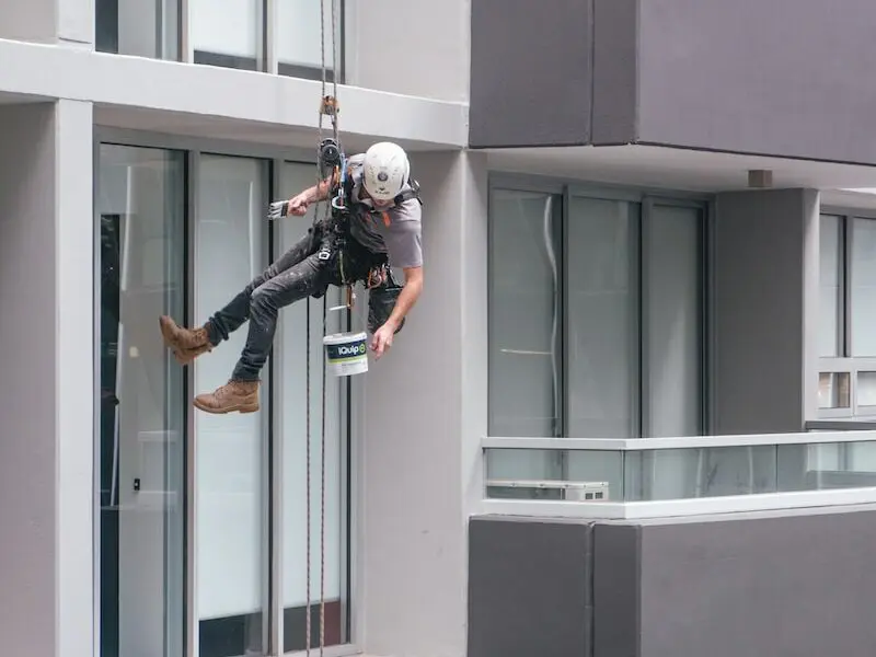 man in black jacket and black pants jumping on window during daytime
