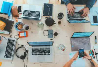 people sitting down near table with assorted laptop computers